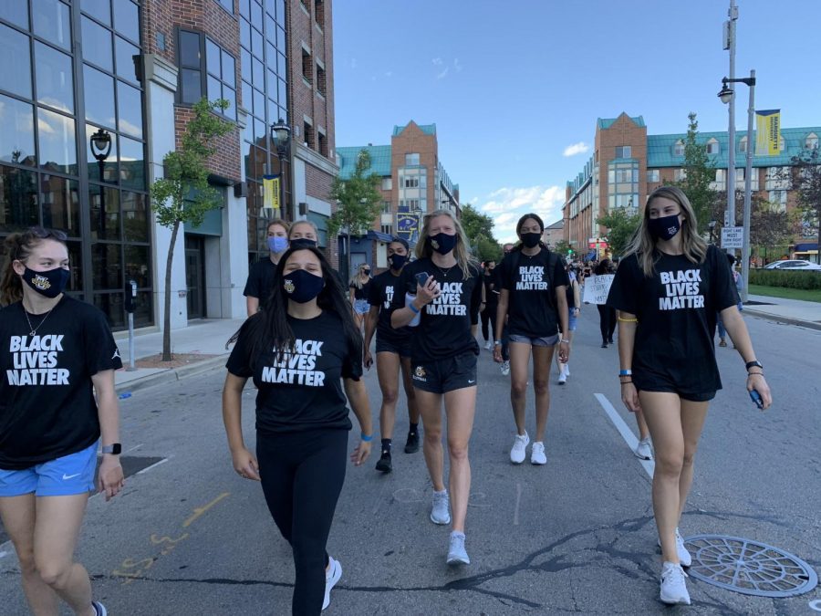 Carsen Murray (second from right) walks with the volleyball team in the athletes march Sept. 4. (Photo courtesy of Marquette Athletics.)