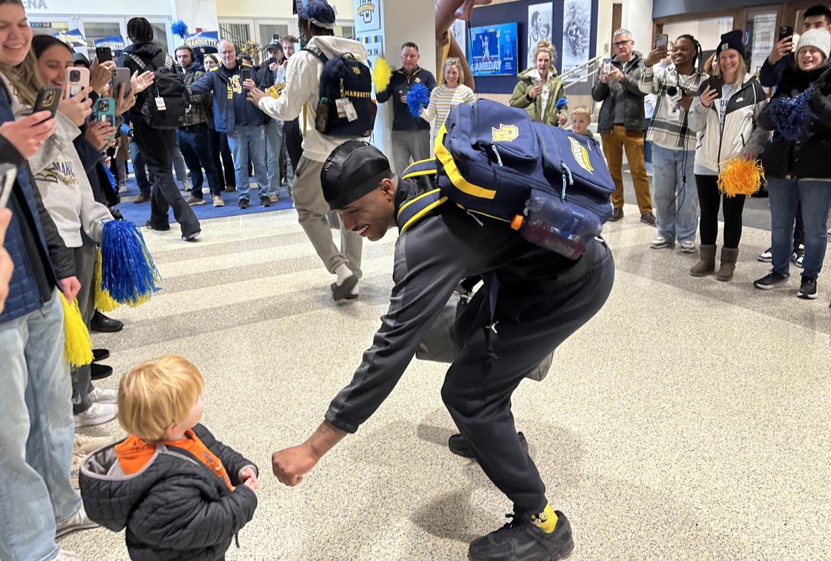 Kam Jones stops to fist-bump a young Marquette basketball fan while making his way out to the team bus.